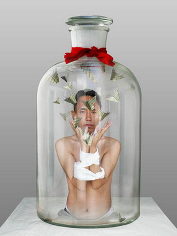 Человек в бутылке, 2009. Фотомонтаж: Запертый в бутылке художник Норцзе (1963 г.р.) Из перевязанных рук он выпускает в пространство бутылки бабочек с тибетскими письменами! Горлышко бутылки перевязано красной лентой. Указание на красный галстук пионеров - молодежной организации компартии? (Норцзе) Фото: Великая Эпоха (The Epoch Times, Германия)  