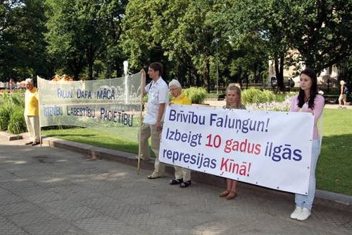 Практикующие держат плакаты, призывающие остановить преследование Фалуньгун в Китае