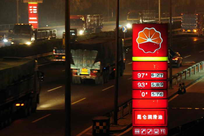 Грузовики мчатся мимо АЗС PetroChina в Пекине 28 июня 2009 года. Чжоу Бинь, сын Чжоу Юнкана, бывшего главы службы безопасности китайского режима, подозревается в коррупции. Он управлял материнской компанией PetroChina  Китайской национальной нефтегазовой корпорацией. Фото: Frederic J. Brown/AFP/Getty Images 