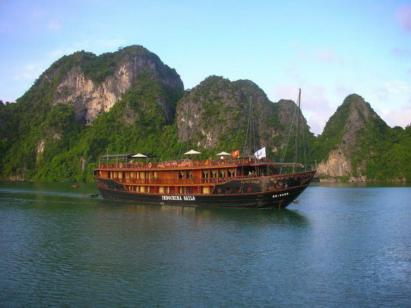 Деревянная джонка (плоскодонная лодка), Indochina Sails, скользит мимо известняковых островов, выступающих из изумрудных вод бухты Халонг. Фото с сайта theepochtimes.com 