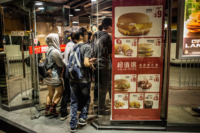 Продемократические активисты убегают от полиции в магазин McDonalds на улице в Монгкоке 29 ноября 2014 года, Гонконг. Хотя полиция зачистила места протестов, столкновения с демократическими активистами в районе Монгкок продолжаются. Фото: Chris McGrath/Getty Images