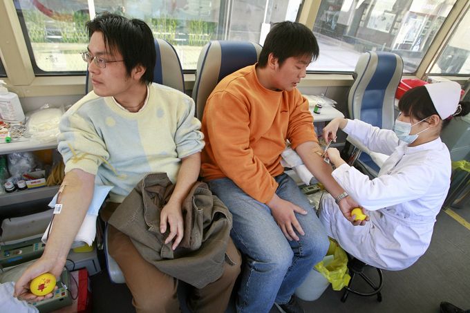 Two Chinese men donate blood at a mobile bloodbank bus in Beijing, 17 November 2007. Young Beijing residents are bucking tradition and stepping forward to answer the latest call to duty by city officials -- to donate blood for next year's Olympics as Chinese blood donors did not exists 10 years ago, according to a contemporary US embassy report, and hospitals had to rely on a high-risk market in blood that was bought and sold with little medical supervison. AFP PHOTO/TEH ENG KOON (Photo credit should read TEH ENG KOON/AFP/Getty Images)