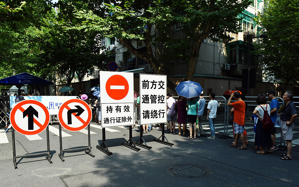 Люди проходят через милицейский пост по проверке безопасности в окрестностях Западного озера в Ханчжоу, Китай, 20 августа 2016 г. Фото: STR/AFP/Getty Images