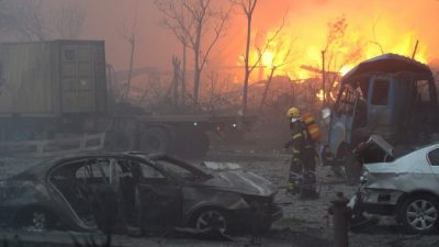 Пожарный проходит мимо искорёженных автомобилей после серии взрывов в городе Тяньцзинь, 13 августа 2015 года. Фото: STR/AFP/Getty Images