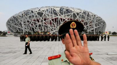 Китайский военизированный полицейский пытается заблокировать фотоснимки репетиции военного парада у Олимпийского стадиона в Пекине 21 июля. (Mark Ralston / AFP / Getty Images)