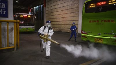 Женщина-волонтер из Blue Sky Rescue дезинфицирует участок автобусной станции, 7 марта 2020 года, Пекин, Китай. Kevin Frayer/Getty Images