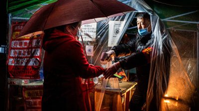 Сотрудник проверяет температуру жительницы перед входом в жилое сообщество города Муданьцзян провинции Хэйлунцзян, 20 апреля 2020 года. STR/AFP via Getty Images