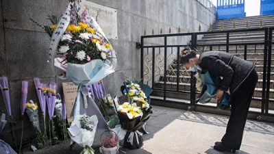 Жительница Уханя преподносит цветы в память погибших во время вспышки COVID-19, 4 апреля 2020 года. Getty Images