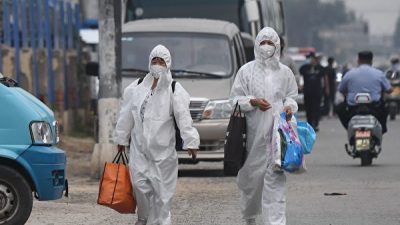 Две женщины в защитных костюмах идут по улице возле закрытого рынка «Синьфади» в Пекине 13 июня 2020 года. GREG BAKER/AFP via Getty Images