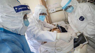 Врач смотрит на изображение, во время обследования пациента с COVID-19, в больнице Уханьского общества Красного Креста 16 февраля 2020 года. STR/AFP via Getty Images