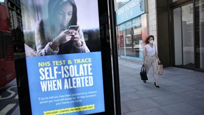 Женщина проходит мимо рекламы NHS Test and Trace на Оксфорд-стрит, где магазины вновь открываются после  вспышки COVID-19, Лондон, Великобритания, 15 июня 2020 года. Dan Kitwood/Getty Images