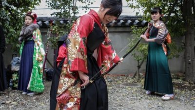 Участница натягивает тетиву лука во время мероприятия по стрельбе  из лука на церемонии совершеннолетия в храме Сандзюсангэндо, Киото, Япония, 17 января,2016. Фото: Taro Karibe/Getty Images