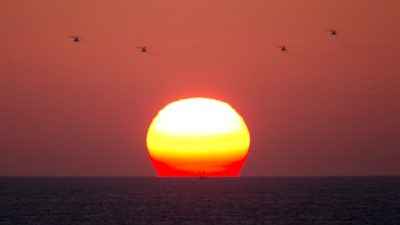 Израильские армейские вертолеты пролетают над Средиземным морем на закате возле израильского портового города Ашдод. Фото: MENAHEM KAHANA/AFP/Getty Images