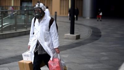 Мужчина в маске несёт вещи, которые он купил в супермаркете Уханя, Китай, 30
марта 2020 года. Ноэль Селис/AFP через Getty Images