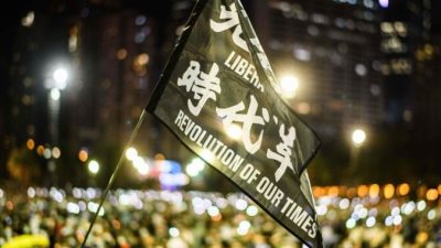 Участники митинга поднимают флаг с надписью «Освободите Гонконг, революция нашего времени» во время акции при свечах в парке Виктория в Гонконге 4 июня 2020 года. ANTHONY WALLACE/AFP via Getty Images