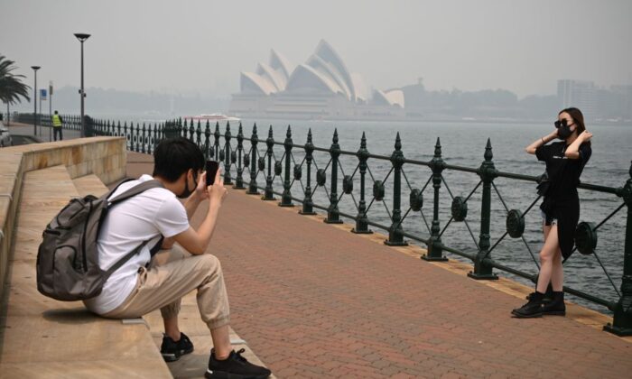 Туристы в масках фотографируются на фоне Оперного театра, окутанного дымом из-за близлежащих лесных пожаров в Сиднее