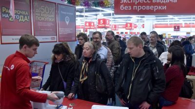 Люди стоят в очереди в торговом центре в центре Москвы 15 декабря 2014 года. Россияне чувствуют себя уязвленными в связи с падением рубля, но одним несколько парадоксальным результатом стало резкое увеличение расходов, поскольку раньше потребители скупали электронику, мебель и автомобили. цены растут. (Кирилл Кукдрявцев / AFP / Getty Images)