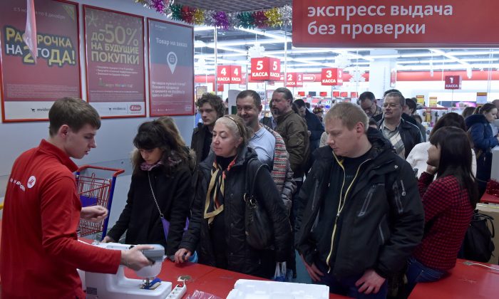 Люди стоят в очереди в торговом центре в центре Москвы 15 декабря 2014 года. Россияне чувствуют себя уязвленными в связи с падением рубля, но одним несколько парадоксальным результатом стало резкое увеличение расходов, поскольку раньше потребители скупали электронику, мебель и автомобили. цены растут. (Кирилл Кукдрявцев / AFP / Getty Images)