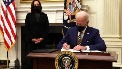 Президент США Джо Байден подписывает указ, а вице-президент Камала Харрис наблюдает во время мероприятия по экономическому кризису в Парадной столовой Белого дома в Вашингтоне, округ Колумбия, 22 января 2021 года. Alex Wong/Getty Images