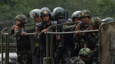 Китайская военизированная полиция готовится к поездке на грузовиках во время церемонии «демонстрации силы» в Урумчи 29 июня 2013 года. Китайский режим пересматривает законы, чтобы предотвратить утечку военной информации. (МАРК РАЛСТОН / AFP / Getty Images)