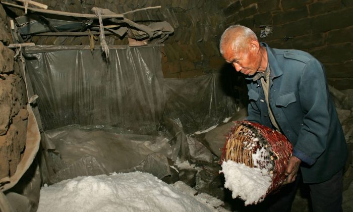Китайский фермер насыпает соль в кучу соли в деревне Лицзява в уезде Цзычжоу, провинция Шэньси, Китай, 31 марта 2006 г. (China Photos / Getty Images)