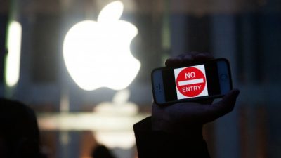Протестующий держит айфон с надписью «Вход запрещён» у магазина Apple на Пятой авеню в Нью-Йорке, 23 февраля. Фото: Bryan Thomas/Getty Images