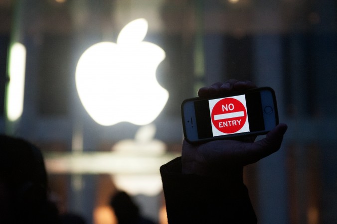 Протестующий держит айфон с надписью «Вход запрещён» у магазина Apple на Пятой авеню в Нью-Йорке, 23 февраля. Фото: Bryan Thomas/Getty Images
