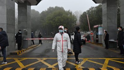 Охранник в защитном снаряжении стоит у входа в Центр по контролю и профилактике заболеваний провинции Хубэй, Китай, 1 февраля 2021 года. Hector Retamal/AFP via Getty Images