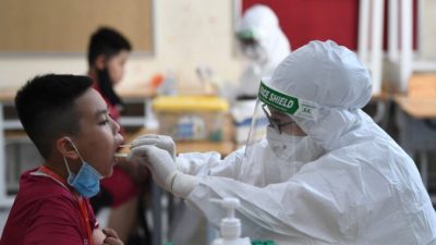 Медицинский работник в защитном костюме (PPE) берёт мазок на COVID-19 у ученика частной школы Vinschool в Ханое, Вьетнам, 22 мая 2021 г. Nhac Nguyen / AFP via Getty Images