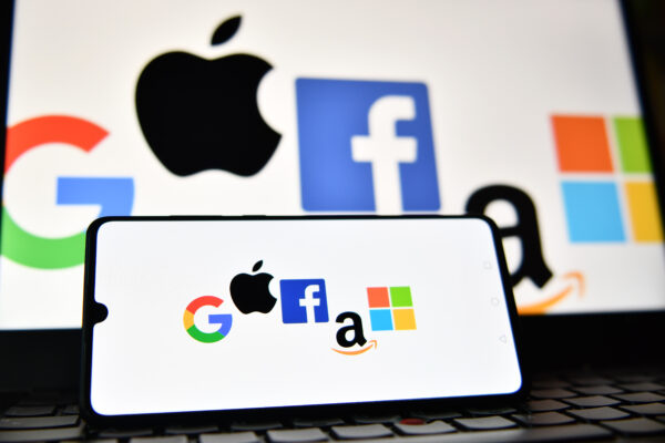 2 фото На фотографии показаны логотипы Google, Apple, Facebook, Amazon и Microsoft, отображаемые на мобильном телефоне и экране ноутбука. 