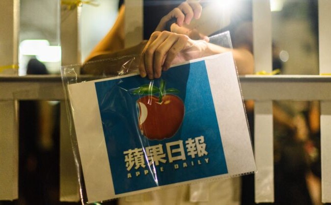 Сторонник держит плакат с логотипом газеты Apple Daily возле офисного здания медиакомпании в Гонконге рано утром 24 июня 2021 г. Anthony Wallace/AFP via Getty Images