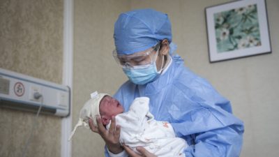 Медсестра держит ребёнка на руках в частной акушерской больнице в городе Ухань, провинция Хубэй, Китай, 21 февраля 2020 г. Getty Images