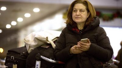 Французская журналистка Урсула Готье, репортер в Китае французского новостного журнала L'Obs, проверяет свой мобильный телефон в ожидании в международном аэропорту Пекин Столичный, 31 декабря 2015 г. (AP Photo / Mark Schiefelbein)