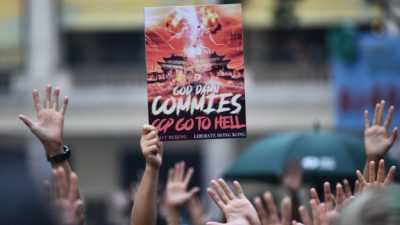Протестующий держит плакат с надписью «Проклятые коммуняки, КПК (Коммунистическая партия Китая) иди в ад» на митинге в районе Ванчай в Гонконге 1 октября 2019 года. ANTHONY WALLACE/AFP via Getty Images