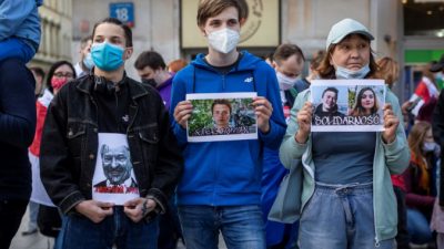 Протестующие держат в руках фотографии активиста белорусской оппозиции Романа Протасевича (в центре) и его русской подруги Софии Сапеги (справа) во время демонстрации белорусов, проживающих в Польше, и поляков перед офисом Европейской комиссии в Варшаве 24 мая 2021 года. WOJTEK RADWANSKI/AFP via Getty Images