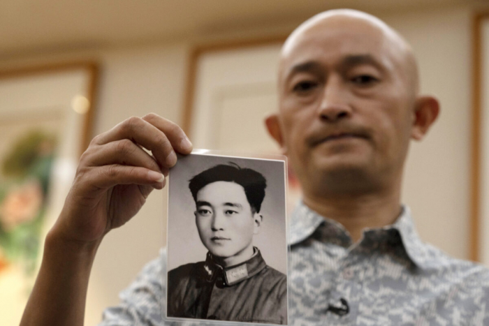 Чжан Хай держит фотографию своего отца, сделанную в молодости. 16 октября 2020 г., COVID-19