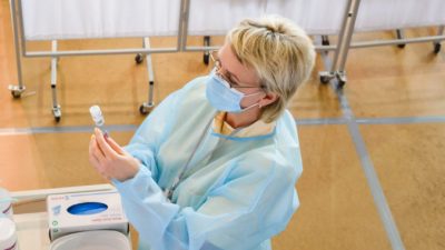 Медицинский работник готовит шприц с вакциной AstraZeneca в спортивном зале местного сообщества, переоборудованном в центр вакцинации в Вентспилсе, Латвия, 30 марта 2021 г. Gints Ivuskans/ AFP via Getty Images)