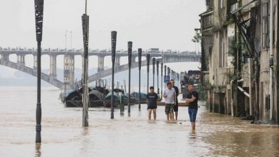 Люди идут вдоль реки Жунцзян после проливных дождей в Ронгане, в южном китайском регионе Гуанси, 2 июля 2021 г. Фото: STR / AFP через Getty Images