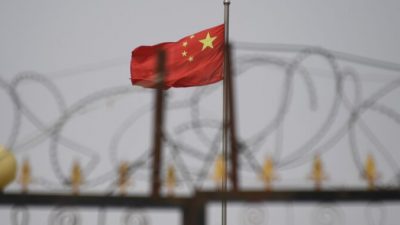 Флаг коммунистической партии Китая за колючей проволокой на жилом комплексе в Янгисаре, к югу от Кашгара, в западном регионе Китая Синьцзян, 4 июня 2019 г. (Greg Baker / AFP via Getty Images)