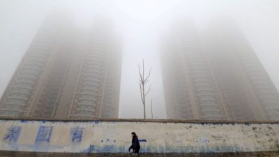 Женщина в маске проходит мимо зданий в Ханьдане, провинция Хэбэй, Китай, 12 января 2019 г. Stringer/Reuters