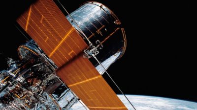 Гигантский космический телескоп «Хаббл» подвешен в космосе с помощью системы удалённого манипулятора (RMS) Discovery после развёртывания части его солнечных панелей и антенн 25 апреля 1990 г. NASA via AP