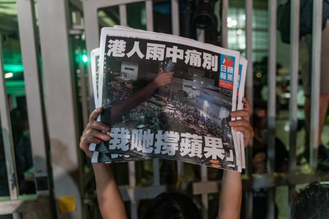 Читатели на закрытых главных воротах офисов Apple Daily после того, как последние газеты компании были напечатаны в типографии в Гонконге 24 июня 2021 г. (Anthony Wallace/AFP via Getty Images)