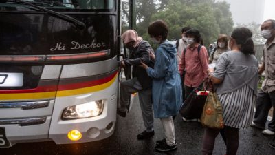 Люди садятся на автобус до центра эвакуации 4 июля 2021 года в Атами, Сидзуока, Япония. Спасательная операция продолжается после того, как в субботу в японском курортном городе Атами произошел оползень, вызванный проливным дождем, в результате чего двое погибли и около двадцати человек пропали без вести. Yuichi Yamazaki/Getty Images