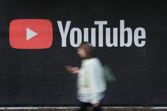 Женщина со смартфоном проходит мимо рекламного щита YouTube в Берлине 27 сентября 2019 г. (Sean Gallup/Getty Images)