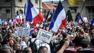 Протестующие во время демонстрации против обязательных пропусков COVID-19 для доступа в общественные места, рядом с Ecole Militaire в Париже, Франция, 7 августа 2021 г. Stephane De Sakutin/AFP