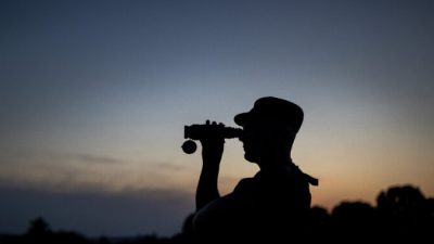 Сотрудник Государственной пограничной службы Литвы смотрит в бинокль во время патрулирования на границе с Беларусью, недалеко от села Пурвенай, Литва, 9 июля 2021 г. Mindaugas Kulbis/AP Photo