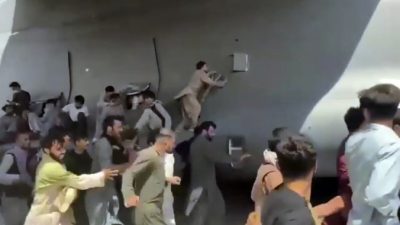 Сотни людей бегут рядом с транспортным самолётом C-17 ВВС США, некоторые забираются на самолёт, когда он движется по взлётно-посадочной полосе международного аэропорта в Кабуле, Афганистан, 16 августа 2021 г. (Verified UGC via AP)