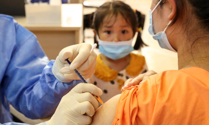 Ребёнок наблюдает, как женщина получает вакцину COVID-19 Китайской национальной биотехнологической группы (CNBG) в Наньтуне, в восточной провинции Китая Цзянсу, 5 июля 2021 г. (STR / AFP через Getty Images)