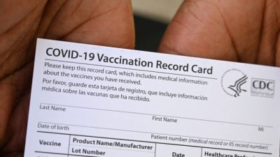 Медицинский работник показывает карточку вакцинации COVID-19 во время посещения клиники вакцинации и здоровья в центре здравоохранения QueensCare в латиноамериканском районе Лос-Анджелеса, Калифорния, 11 августа 2021 г. (Robyn Beck/AFP via Getty Images)