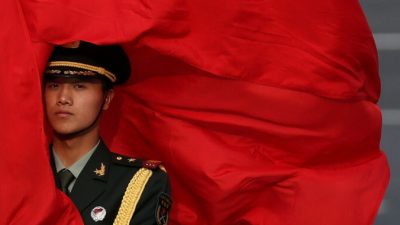 Ветер развевает красный флаг в лицо китайскому охраннику перед церемонией встречи премьер-министра Австралии Джулии Гиллард у Большого зала народа 9 апреля 2013 года в Пекине, Китай. (Фото Фэн Ли / Getty Images)